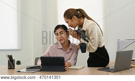 Young Female Employee Telling Gossips, Whispering Into Female Colleague Ear Int Office
