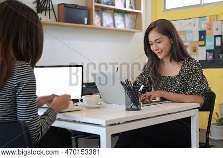 Two Creative Women Colleagues Working On Project Together At Office.
