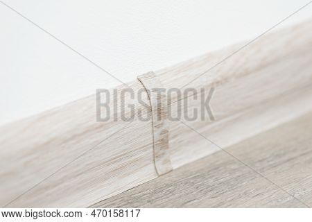 Close Up Shot Of Plinth Between White Wall And Linoleum Floor. Connector Between Two Pieces Of Plint