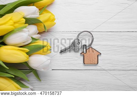 Beautiful Spring Flowers And Key With Trinket In Shape Of House On White Wooden Table, Flat Lay