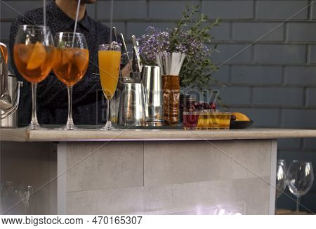 Glasses Of Cocktails On The Bar. Bartender Pours A Glass Of Sparkling Wine With Red Alcohol. Barman 