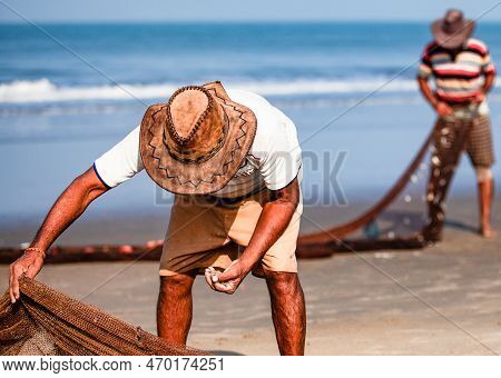 Morjim, North Goa, India , 29 March 2016: Fisherman In A Hat Clean The Fishing Net On The Ocean. Man