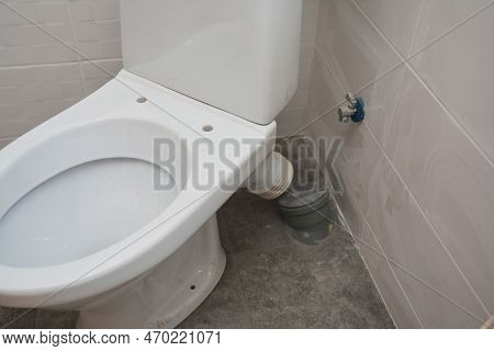 Close Up On White Toilet Bowl Installation And Plumbing Connecting Toilet Pan Connector To The Waste