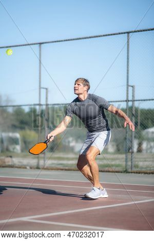 Man Playing Pickleball Game, Hitting Pickleball Yellow Ball With Paddle, Outdoor Sport Leisure Activ