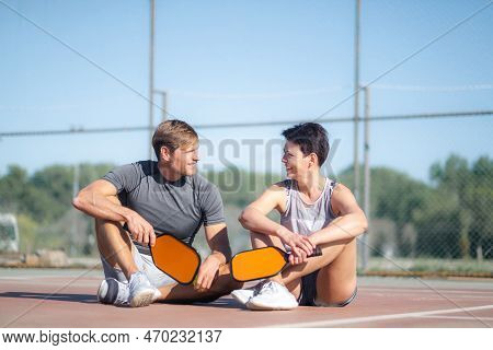 Pickleball Game, Relaxing Pickleball Players Couple With Yellow Ball With Paddle Sitting After Game,