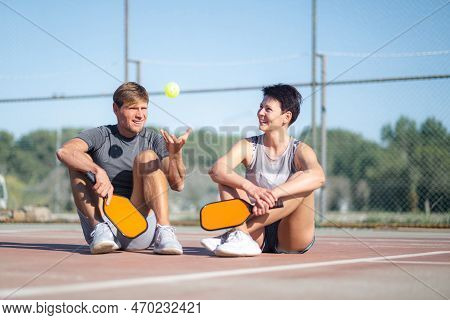 Pickleball Game, Relaxing Pickleball Players Couple With Yellow Ball With Paddle Sitting After Game,