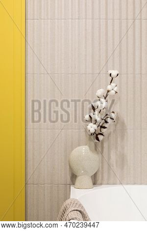 Modern Bright And Yellow Bathroom With Lamella Wall. Big White Bath With Btrown Towel And Dried Flow