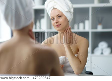 Young Woman Sits In The Bathroom In Front Of The Makeup Mirror And Does Cosmetic Procedures. Beautif