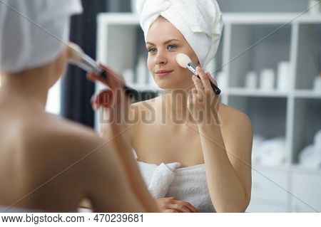 Young Woman Sits In The Bathroom In Front Of The Makeup Mirror And Does Cosmetic Procedures. Beautif