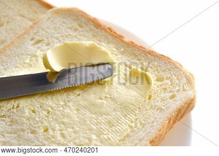 Butter On Bread On A White Plate. A Knife Spreading Butter On Bread.
