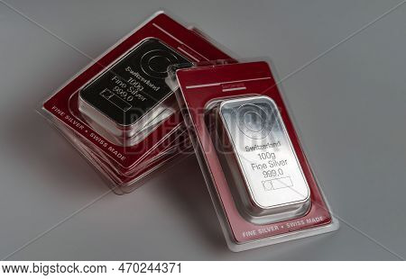 Several Minted Silver Bars Weighing 100 Grams In Transparent Blister Pack On A Grey Background.