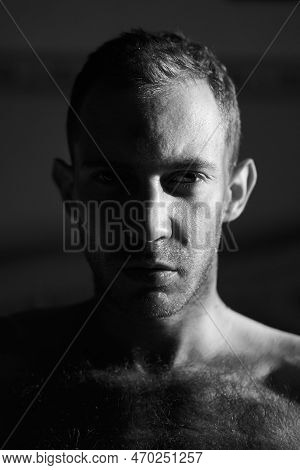 Portrait Of Handsome Man In Hard Side Light Facing Camera. Half Of Attractive Male Face Lit By The S