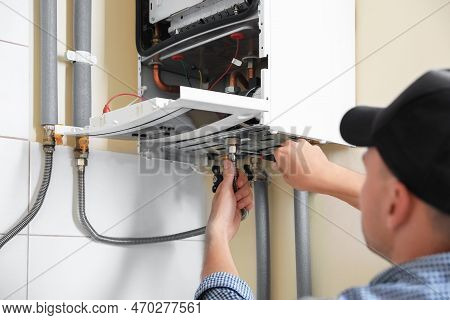 Man Repairing Gas Boiler With Waterpump Plier Indoors, Closeup