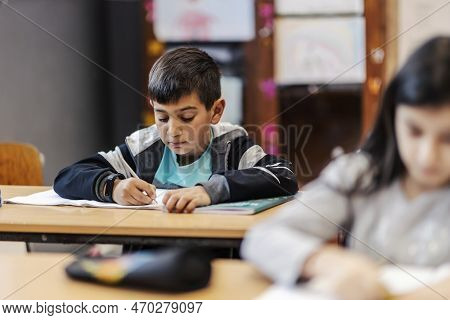A Clever Indian Boy Writes Downright Answers In Notebook At Classroom.