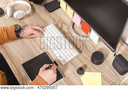Close Up Of Hand Holding Stylus On Graphics Tablet For Retouching Work. A Photographer Using An Edit