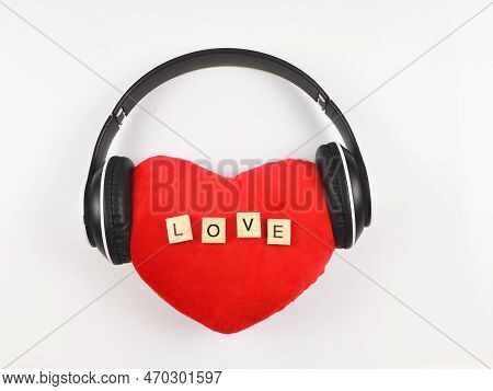 Top View Or Flat Lay Of Red Heart Pillow With Wooden Letters L O V E  Coverd With Headphones On Whit