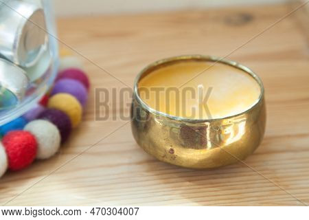 Gold candle and tinsha on a wood table.