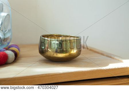 Gold candle and tinsha on a wood table.