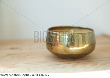 Gold candle and tinsha on a wood table.