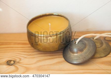 Gold Candle And Tinsha On A Wood Table.