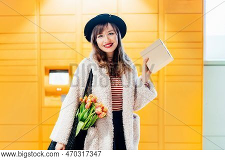 Portrait Of Smiling Fashion Woman With Box Near Modern Postal Automatic Mail Terminal With Self Serv