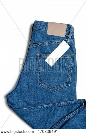 Blue Jeans Pants And Price Tag Isolated On White Background. Denim Background, Texture, Mockup. Fash