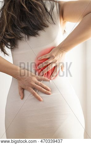 Pain In The Body. Studio Shot Of A Young Woman With Dark Brown Hair. A Woman Suffers From Back Pain.