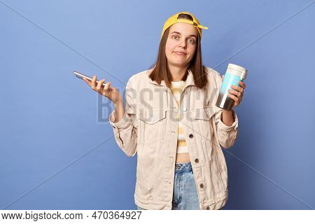Portrait Of Confused Uncertain Teenager Girl Wearing Baseball Cap And Jacket Posing Isolated Over Bl