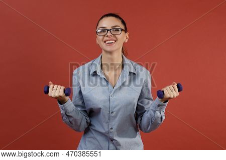 Successful Young Modern Businesswoman In Blue Shirt Warming Up With Dumbbells At Office While Workin