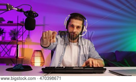 Cybersportsman In A Neon Room. Gamer Bearded Guy, In Gaming Headphones, Challenges. Lifestyle Gamer,
