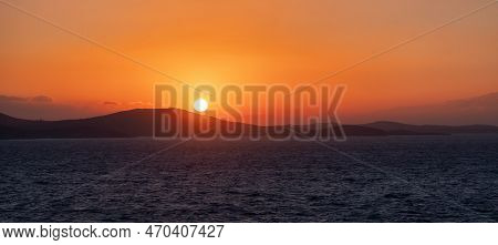 Rocky Island On Mediterranean Sea. Rinia Near Mikonos, Greece, Europe. Nature Background. Sunrise Sk