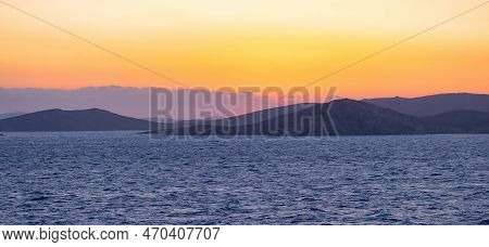 Rocky Island On Mediterranean Sea. Rinia Near Mikonos, Greece, Europe. Nature Background. Sunrise Sk