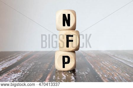 Three Wooden Cubes With Letters - Nfp On Yellow Table, Space For Text In Right. Front View Concepts,