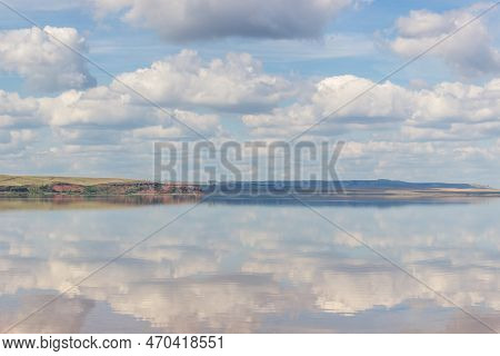 Lake With Clouds In The Sky, Red Hill With Forests On Background