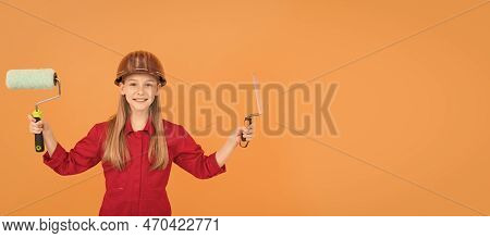 Happy Teen Child In Builder Hard Hat With Paint Roller And Spatula On Orange Wall