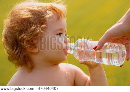 Baby Kids Drinking Water From Mother Hands. Baby Boy With Curly Blond Hair Drinking Water In The Par