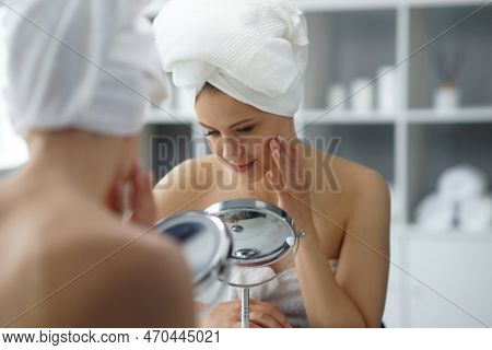 Young Woman Sits In The Bathroom In Front Of The Makeup Mirror And Does Cosmetic Procedures. Beautif
