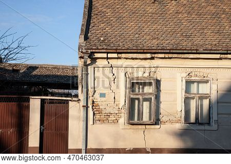 Cracked Facade Of A Stone Wall Of An Old And Decaying Building, Heavily Needing Renovation On An Aba