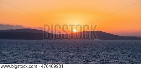 Rocky Island On Mediterranean Sea. Rinia Near Mikonos, Greece, Europe. Nature Background. Sunrise Sk