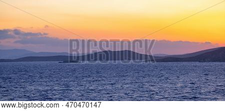 Rocky Island On Mediterranean Sea. Rinia Near Mikonos, Greece, Europe. Nature Background. Sunrise Sk