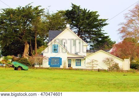 Historical Colonial Style Home Besides Cypress Trees And A Lush Field Taken In Mendocino, Ca