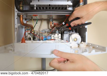Man Repairing Gas Boiler With Waterpump Plier, Closeup