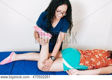 Knee Flexion Physiotherapy To Female Patient. Chiropractor Stretching Knee To Lying Female Patient, 