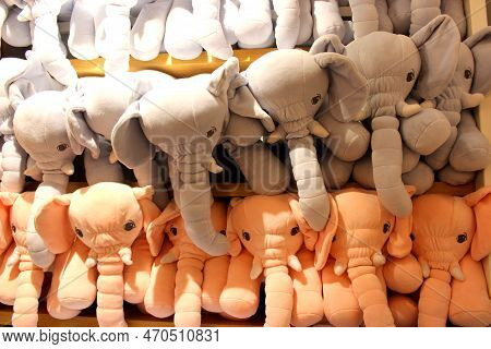 Stuffed Animals Arranged In A Shelf For Sale. Grey And Peach Colored Elephants Stuffed In A Shelf. C