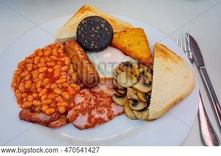White Board With Full English Breakfast With Bacon, Fried Egg, Beans, Tomato, Roasted Sausage, Black