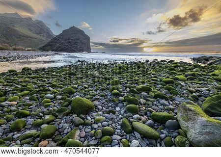 Sunset Over Land And Sea: A Rocky Beach View