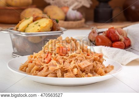 Stewed Cabbage - Bigos In A White Porcelain Plate Against The Background Of Pickled Vegetables And B