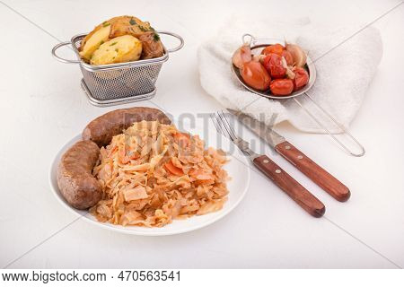 Braised Cabbage - Bigos And Grilled Sausage In A White Porcelain Plate Against The Background Of Rus