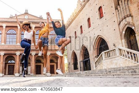 Three Young Happy Women Enjoying Summer Holidays. Millennial Female Having Fun Jumping Together At O