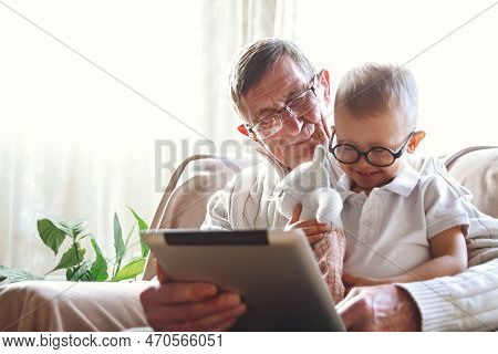 Elderly Grandfather And His Little Grandson Use A Tablet Device Together